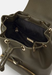 Olive green textured leather bucket bag with gold hardware, featuring drawstring closure and a zippered interior pocket.