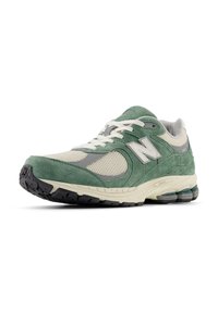 Green and beige running shoes with mesh and suede materials, featuring a thick rubber sole, padded collar, and reflective accents.