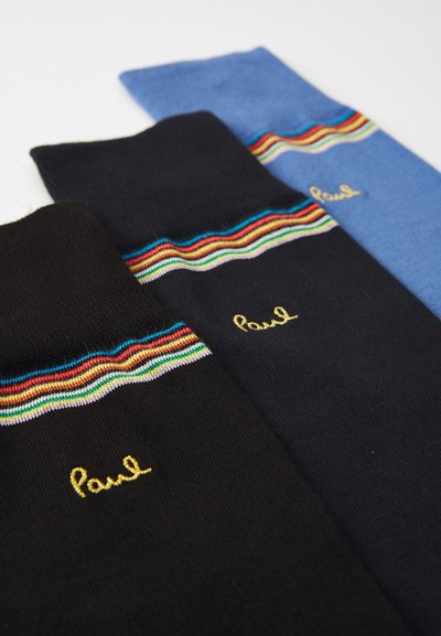 Drei Paar Socken: zwei schwarze mit multicoloren Streifen und goldener "Paul"-Stickerei sowie ein hellblaues Paar mit einem ähnlichen Streifen.