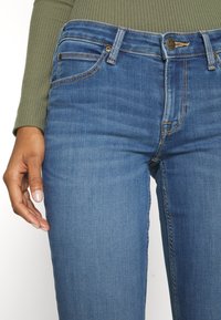 Blå denimjeans med en figurnära design, som har en medelhög midja, subtila sömmar och framfickor. Mjuk textur och hållbart tyg.