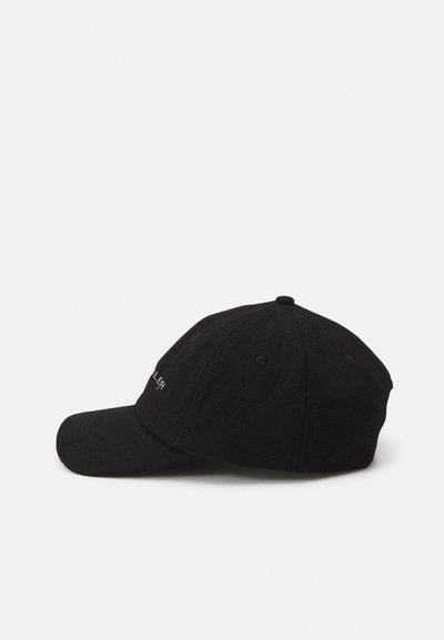 Casquette de baseball noire en tissu texturé avec une visière courbée, comportant un texte brodé sur le devant et des trous de ventilation sur les côtés.