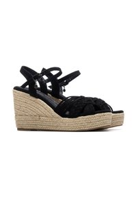 Sandalias de cuña de ante negro con detalles trenzados, plataforma estilo yute y correas ajustables en el tobillo. Plantilla negra suave y suela texturizada.