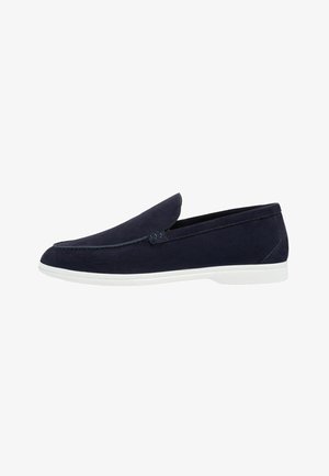 Mocassin en daim bleu marine avec semelle en caoutchouc blanche, design sans lacets et couture minimale le long du bord supérieur.