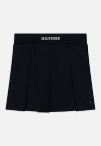 Gonna nera plissettata in cotone con un elastico in vita, con la scritta "HILFIGER" in bianco. Piccolo logo accento vicino all'orlo.