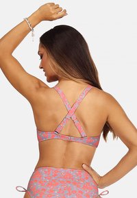 Wielokolorowy biustonosz bikini z kwiatowym wzorem, regulowanymi krzyżującymi się ramiączkami oraz zapięciem na klamrę. Materiał wydaje się gładki i elastyczny.