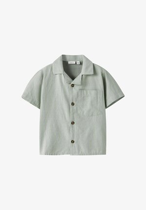 Majica kratkih rukava zelene boje izrađena od teksturiranog materijala, s ovratnikom, zatvaranjem na dugmad i lijevim džepom na prsima u kvadratnom obliku.