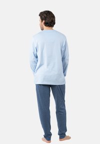 Chemise à manches longues bleu clair avec un empiècement rectangulaire au dos, associée à un pantalon de pyjama rayé bleu et blanc, fabriqué en tissu de coton doux.