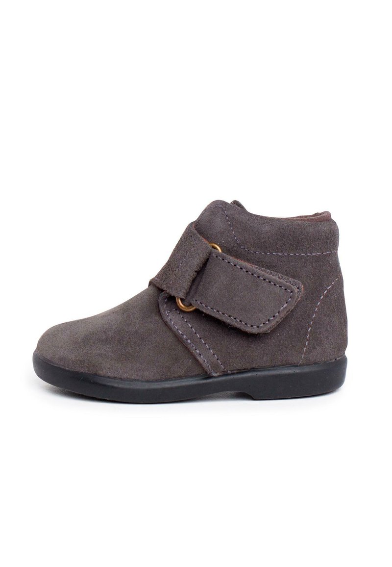 Stivaletto in suede grigio con cinturino in Velcro, punta arrotondata e suola in gomma nera. Le cuciture lungo i bordi esaltano il design.
