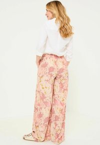 Pink and yellow floral patterned wide-leg pants with an elastic waistband, paired with a white button-up shirt and slide sandals.