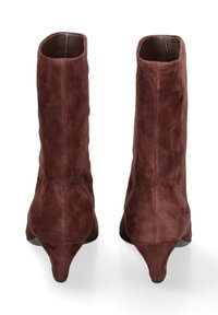 Stivaletti in suede marrone con un design affusolato, gambale corto e tacchi di 5 centimetri. Texture liscia con dettagli minimalisti, che mostrano una finitura senza soluzione di continuità.