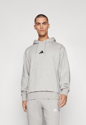 Világosszürke kapucnis pulóver, puha anyagból készült, elől zsebbel, húzózsinórral ellátott kapucnival és fekete Adidas logóval a mellkasán.
