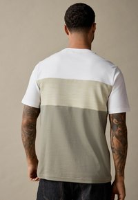 Kortærmet T-shirt med en hvid overdel og tekstureret lysegrøn underdel, med en lige kant og diskrete detaljer.
