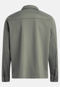 Camisa de manga larga en tela verde oliva. Presenta un cuello, puños con botón y un corte recto. Textura suave con un detalle mínimo.