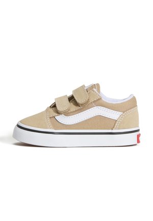 Beige og hvid lav sneakers med to velcrobånd og en hvid gummisål med sort kant, set fra siden på hvid baggrund.