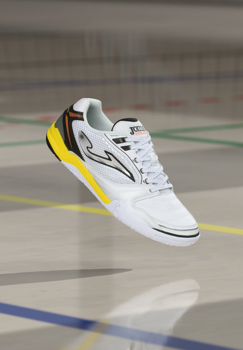 Λευκό αθλητικό παπούτσι με κίτρινες και μαύρες αποχρώσεις, με υφασμένο επάνω μέρος, καμπυλωτό σχέδιο και ελαφριά σόλα.