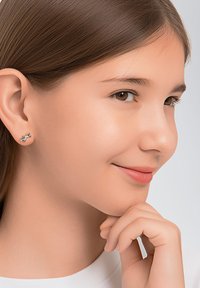 Silberne Ohrstecker in Form eines Kaninchens, die eine glatte Metalloberfläche vor einem hellen Hintergrund zeigen. Das Modell hat braune Haare und einen neutralen Gesichtsausdruck.