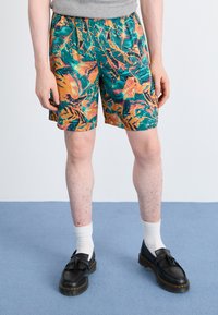 Pantaloni scurți multicolora cu un imprimeu tropical, cu nuanțe de verde, portocaliu și violet. Fabricat dintr-un material ușor, cu talie elastică, lungime deasupra genunchiului.