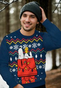 Maglione blu lavorato a maglia con fiocchi di neve bianchi, un motivo zigzag colorato e una grafica a tema natalizio con orsi polari e ornamenti.