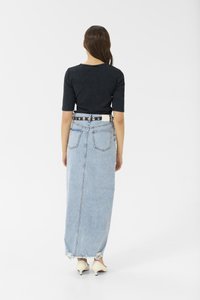 Long light blue denim skirt with a straight cut, frayed hem, and two back pockets, worn with a black fitted top and white belt.