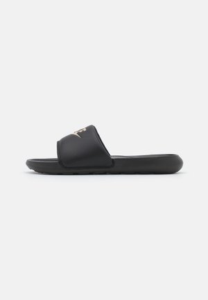 Black slide sandals with a single strap and textured footbed. Features a gold logo accent on the strap. Constructed from synthetic materials.