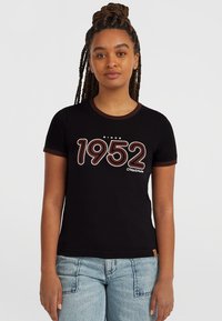 Svart t-shirt med runt brunt kantband, med fet vit och röd text "1952" och "sedan" ovanför, tillverkad av bomull.