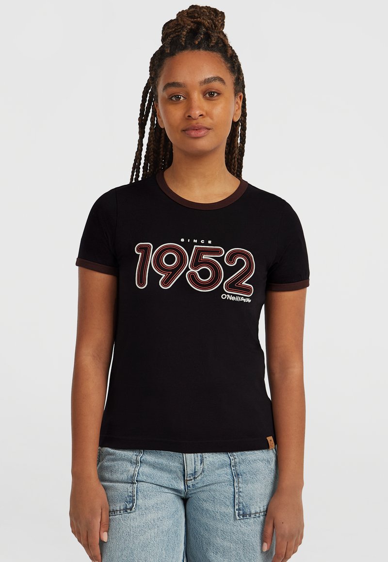 Svart t-shirt med runt brunt kantband, med fet vit och röd text "1952" och "sedan" ovanför, tillverkad av bomull.