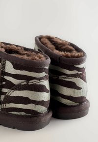 Stivali alla zebra con strisce marroni e argento, foderati con morbido pellicciotto, realizzati in suede testurizzato e dotati di una suola in gomma flessibile.