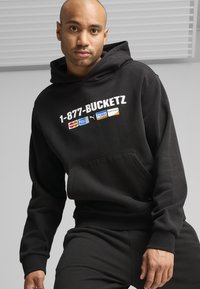 Felpa nera con cappuccio e tasca a marsupio frontale, caratterizzata da una grafica bianca "1-877-BUCKETZ" e loghi del marchio sul petto. Materiale morbido e testurizzato.