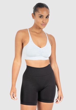 Lichtblauw geribbeld crop top met een geplooid midden, gecombineerd met hoge zwarte shorts. Beide zijn gemaakt van rekbare stof voor comfort.