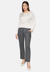 Hvid satin bluse med lange ærmer kombineret med skræddersyede grå bukser med lynlåslomme, afsluttet med spidse hvide hæle.