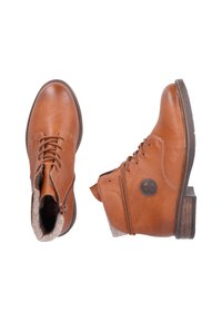 Stivaletti in pelle marrone con accenti testurizzati color tan, punta tonda, chiusura con lacci e patch decorativo con logo. Suola in gomma con tacco impilato.