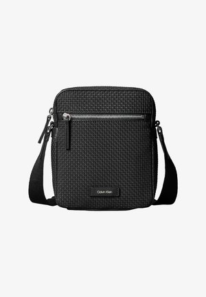 Czarna pleciona torebka na ramię z zamknięciem na zamek u góry, z przednią kieszenią na zamek i materiałowym paskiem na ramię. Ozdobiona logo Calvin Klein.
