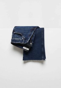 Jean en denim bleu foncé, plié avec une ceinture et une poche visibles, doté d'une fermeture éclair et d'un bouton, et d'un ourlet effiloché.