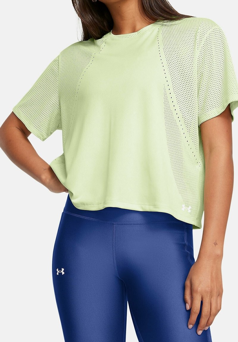 Camiseta atlética cortada de color verde claro con paneles de malla, cuello redondo y mangas cortas, combinada con leggings brillantes de color azul.