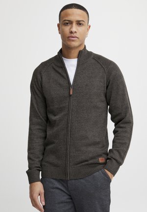 Sudadera de cremallera en gris oscuro con un cuello alto, puños y dobladillo acanalados. Fabricada con una tela texturada, cuenta con una pequeña etiqueta de la marca en el lado inferior.