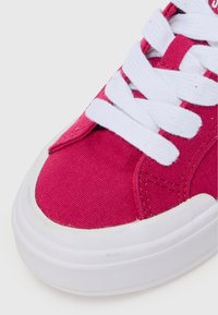 Baskets en toile roses avec des lacets blancs, tige texturée et semelle en caoutchouc arrondie. Présente un embout renforcé et des détails de couture.