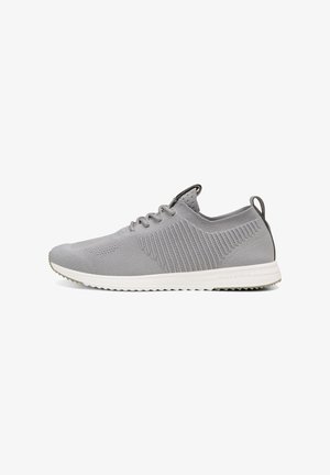 Zapatilla deportiva gris claro de punto con cordones, laterales texturizados, suela blanca, lengüeta en el talón y diseño de perfil bajo para uso casual.