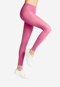 Leggings fucsia in un materiale liscio ed elastico, con un design a vita alta, abbinati a scarpe da ginnastica bianche.