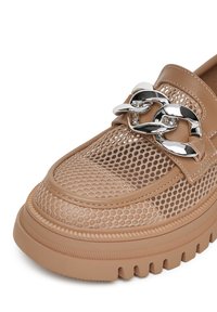 Béžová síťovaná obuv s robustní podrážkou, zdobená hladkým koženým páskem a výrazným kovovým řetízkem přes přední část.