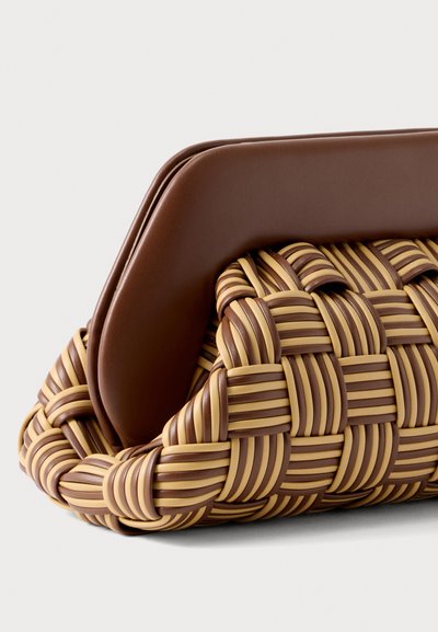 Καφέ και μπεζ υφαντή τσάντα χειρός με ομαλό καφέ σκουρόχρωμο δερμάτινο επάνω κλείσιμο, εμφανιζόμενη σε απλό ανοιχτό φόντο.