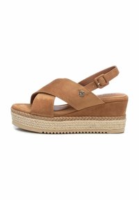 Sandalo in suede marrone con cinturini incrociati, una fascia alla caviglia con fibbia e suola piatta avvolta in juta, dotato di un tacco leggero.