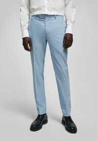 Lichtblauwe op maat gemaakte broek van zachte stof, met een flat front en een slanke pasvorm, gecombineerd met zwarte leren schoenen.