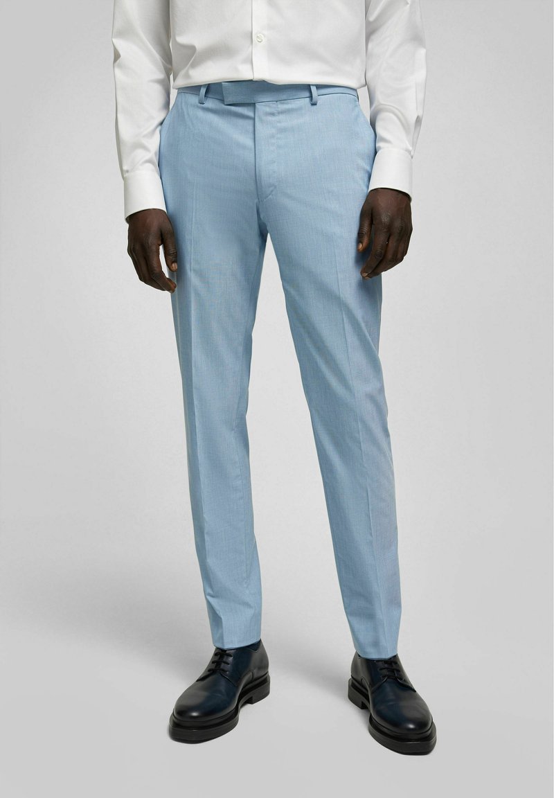 Lichtblauwe op maat gemaakte broek van zachte stof, met een flat front en een slanke pasvorm, gecombineerd met zwarte leren schoenen.