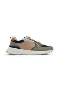 Zapatilla deportiva de hombre con paneles beige, verde, negro y gris, cordones marrones y una suela blanca gruesa, mostrada de perfil sobre un fondo blanco.