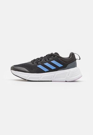 Chaussure de course noire et bleue avec semelle blanche amortie et languette au talon, vue de côté sur un fond uni.