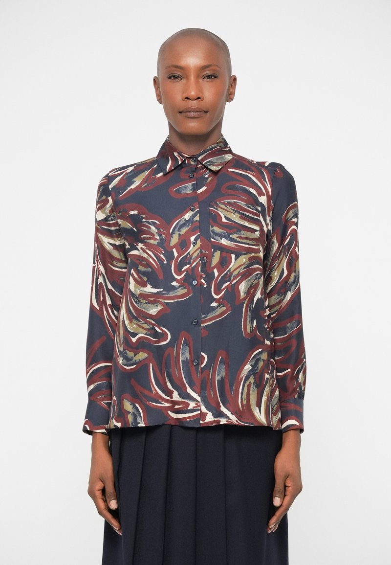 Langærmet bluse i mørk navy silke med flerfarvede bladmønstre. Har en klassisk krave og knaplukning foran. Glat tekstur.