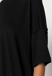 T-shirt nera in cotone morbido, con una vestibilità comoda, maniche corte e scollatura rotonda. Le cuciture sono rifinite in modo ordinato.