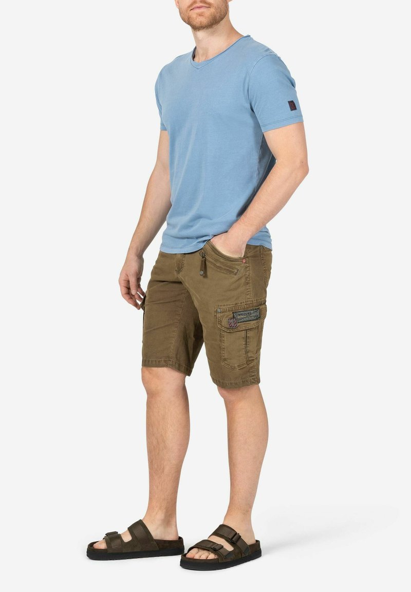 Light blue short-sleeve T-shirt, olive green cargo shorts with pocket detail, and black sandals with multiple straps. Casual outfit.