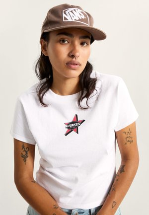 Maglietta bianca di cotone con logo a stella rosso e nero. Cappellino marrone con logo Vans bianco. Maniche corte, scollo rotondo, vestibilità casual.