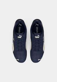 Mørkeblå sneakers med en glat syntetisk overdel, hvide detaljer og teksturerede gummisåler. Har snørebånd og Ortholite indlægssåler for komfort.